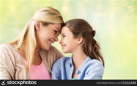 people and family concept - happy smiling girl with mother hugging over holidays lights background. happy girl with mother hugging over lights