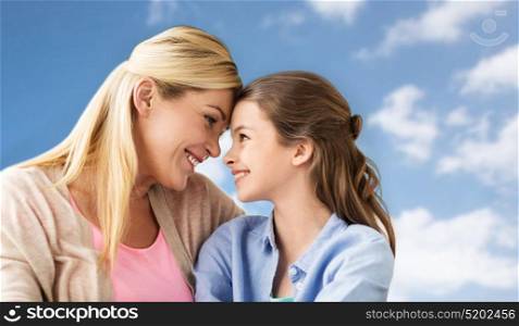 people and family concept - happy smiling girl with mother over blue sky and clouds background. happy family of girl and mother over blue sky
