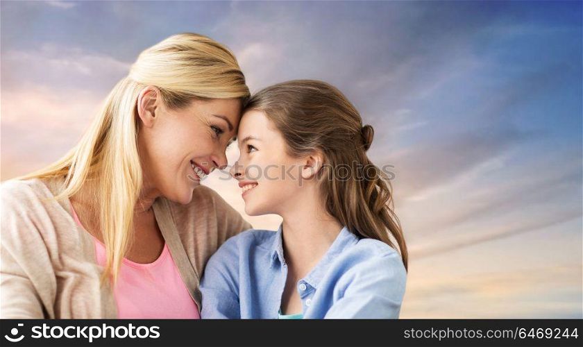 people and family concept - happy smiling mother and daughter over evening sky background. happy smiling mother and daughter over sky