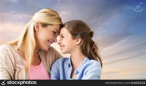 people and family concept - happy smiling mother and daughter over evening sky background. happy smiling mother and daughter over sky