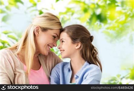 people and family concept - happy smiling mother and daughter over green natural background. happy smiling mother and daughter