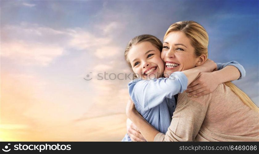 people and family concept - happy smiling mother hugging daughter over evening sky background. happy smiling mother hugging daughter over sky