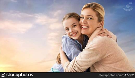 people and family concept - happy smiling mother hugging daughter over evening sky background. happy smiling mother hugging daughter over sky. happy smiling mother hugging daughter over sky