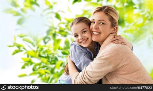 people and family concept - happy smiling mother hugging daughter over green natural background. happy smiling mother hugging daughter. happy smiling mother hugging daughter