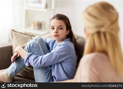 people and family concept - sad girl with mother sitting on sofa at home. sad girl with mother sitting on sofa at home. sad girl with mother sitting on sofa at home