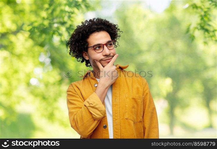 people and fashion concept - thinking man in glasses and yellow jacket over green natural background. thinking man on natural background