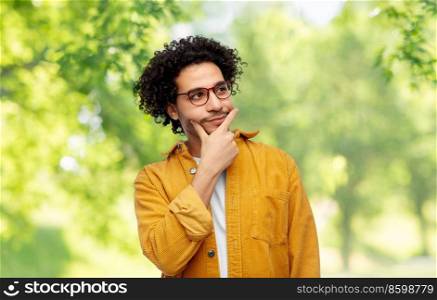 people and fashion concept - thinking man in glasses and yellow jacket over green natural background. thinking man on natural background