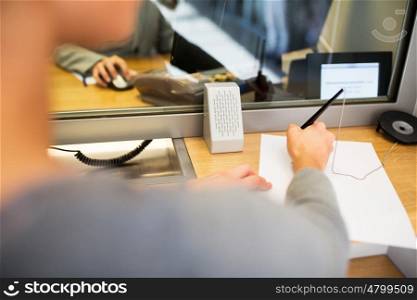 people and finance concept - customer with pen and paper writing application at bank office. customer writing application at bank office