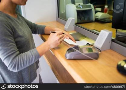 people and finance concept - customer with pen and paper writing application at bank office. customer writing application at bank office
