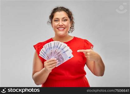 people and finances concept - happy woman in red dress showing euro money banknotes over grey background. happy woman showing euro money banknotes
