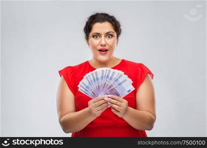 people and finances concept - surprised woman in red dress holding thousands of euro money banknotes over grey background. happy woman holding thousands of money banknotes