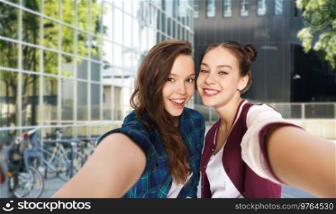 people and friendship concept - happy smiling pretty teenage girls taking selfie over city street or school yard background. happy teenage girls taking selfie on city street