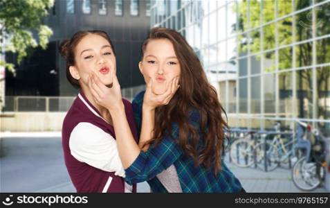 people and friendship concept - happy smiling teenage girls having fun and making faces over city street or school yard background. happy teenage girls having fun in city