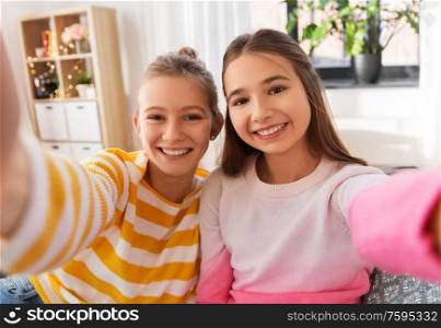 people and friendship concept - happy smiling teenage girls taking selfie at home. happy teenage girls taking selfie at home