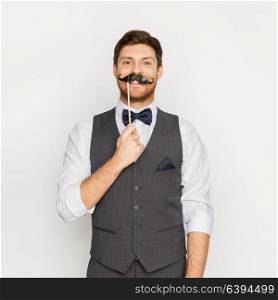 people and fun and concept - happy couple posing with party props. happy young man with fake mustache at party