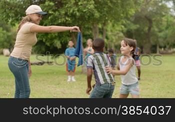 People and fun, group of male and female school kids with young woman working as educator playing game outdoor at summer camp