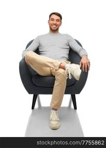 people and furniture concept - happy smiling man sitting in chair over white background. happy smiling man sitting in chair