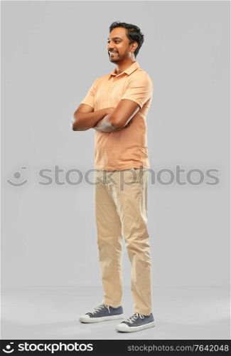 people and furniture concept - portrait of happy smiling young indian man with crossed arms over grey background. portrait of happy smiling young indian man