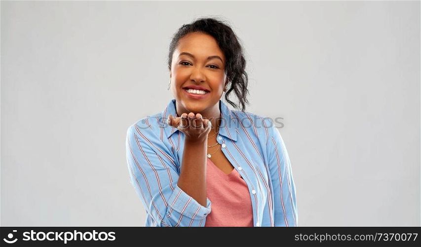 people and gesture concept - happy african american young woman holding something imaginary on empty hand over pink background. happy african woman holding something on hand