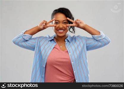 people and gesture concept - happy african american young woman showing peace hand sign over pink background. happy african american woman showing peace