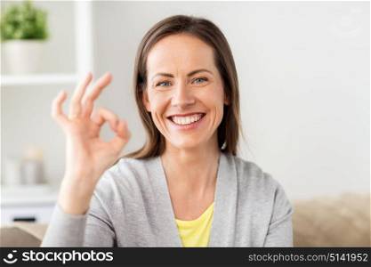 people and gesture concept - happy smiling middle aged woman showing ok hand sign at home. happy smiling woman showing ok hand sign at home
