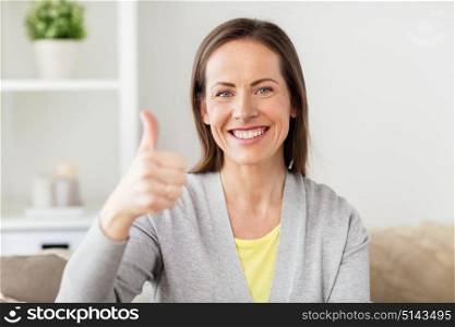 people and gesture concept - happy smiling middle aged woman showing thumbs up at home. happy smiling woman showing thumbs up at home