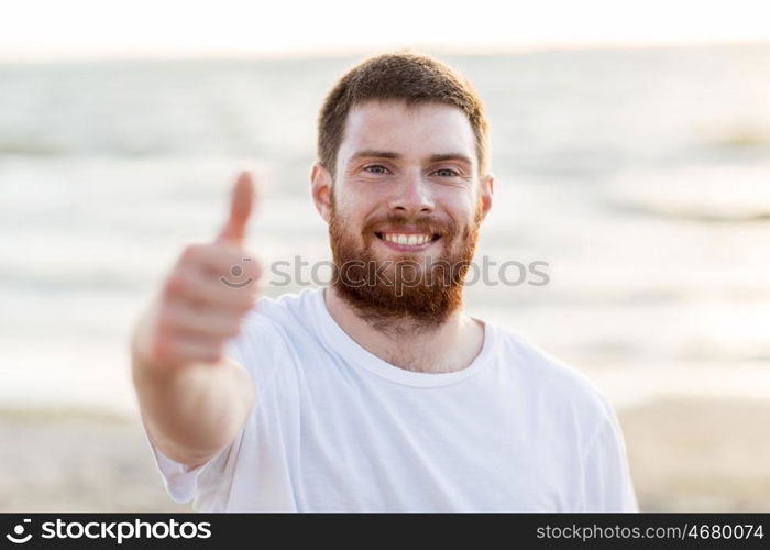 people and gesture concept - happy smiling young man on beach. happy smiling young man on beach