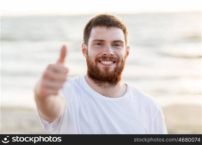 people and gesture concept - happy smiling young man on beach. happy smiling young man on beach