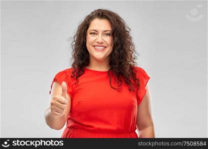 people and gesture concept - happy woman in red dress showing thumbs up over grey background. happy woman in red dress showing thumbs up