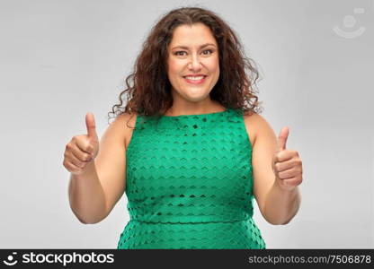 people and gesture concept - happy woman in red green showing thumbs up over grey background. happy woman in green dress showing thumbs up