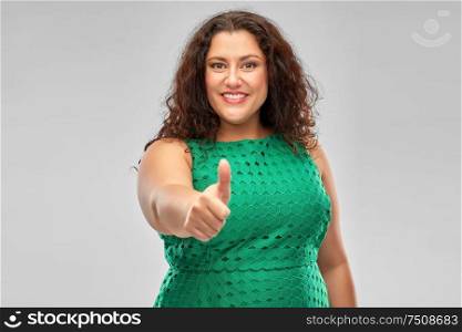 people and gesture concept - happy woman in red green showing thumbs up over grey background. happy woman in green dress showing thumbs up