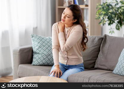 people and health problem concept - unhappy asian woman suffering from pain in in shoulder at home. asian woman suffering from shoulder pain at home