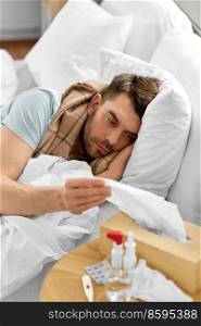 people and health problem concept - unhappy sick man lying in bed at home and taking paper tissue from box. sick man lying in bed at home and taking tissue