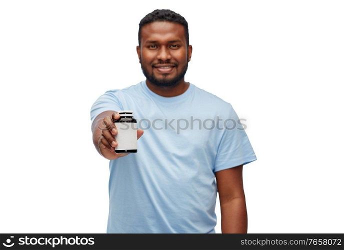 people and healthcare concept - portrait of happy smiling young african american man with medicine jar over white background. smiling african american man with medicine jar