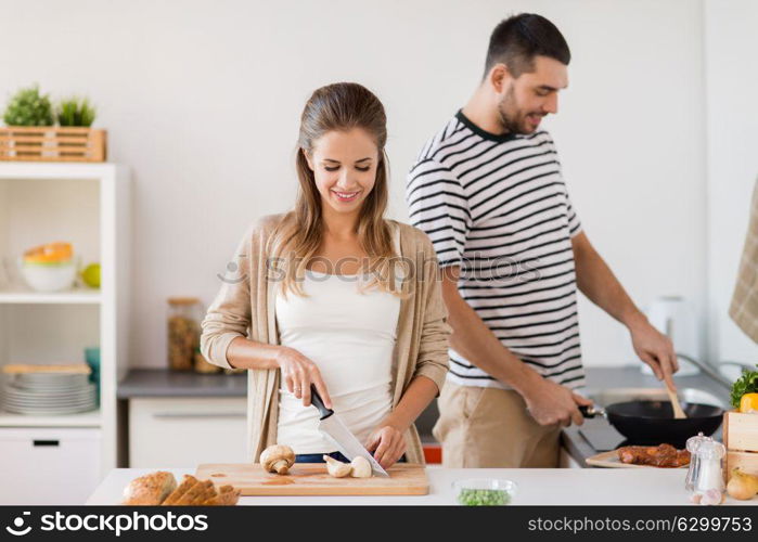 people and healthy eating concept - couple cooking food at home kitchen. couple cooking food at home kitchen