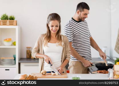 people and healthy eating concept - couple cooking food at home kitchen. couple cooking food at home kitchen