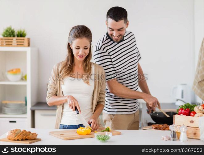 people and healthy eating concept - couple cooking food at home kitchen. couple cooking food at home kitchen