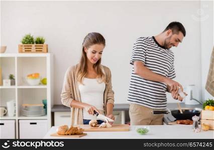 people and healthy eating concept - couple cooking food at home kitchen. couple cooking food at home kitchen