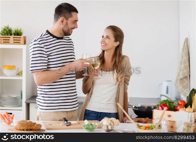 people and healthy eating concept - happy couple cooking and drinking non alcoholic wine at home kitchen. couple cooking food and drinking wine at home