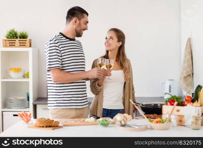 people and healthy eating concept - happy couple cooking and drinking non alcoholic wine at home kitchen. couple cooking food and drinking wine at home