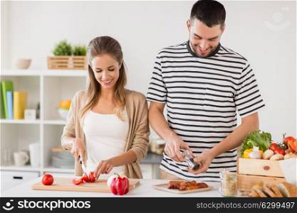 people and healthy eating concept - happy couple cooking food at home kitchen. happy couple cooking food at home kitchen