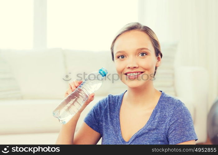 people and healthy lifestyle concept - happy woman with bottle of water at home. happy woman with water bottle at home