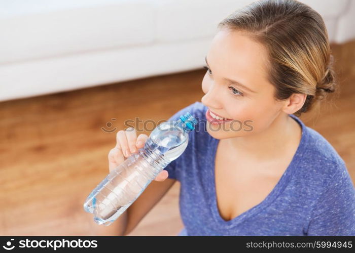 people and healthy lifestyle concept - happy woman with bottle of water at home. happy woman with water bottle at home