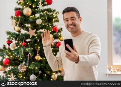 people and holidays concept - happy smiling middle aged man with smartphone having video call at home. man with smartphone having video call on christmas