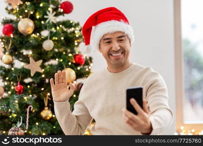 people and holidays concept - happy smiling middle aged man with smartphone having video call at home. man with smartphone having video call on christmas