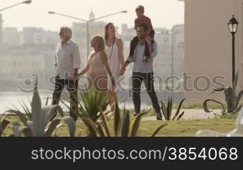 People and holidays, family with man, woman, grandfather, grandmother and child walking and having fun in city park
