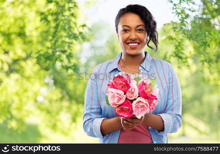 people and international women&rsquo;s day concept - happy african american young woman with bunch of peony flowers over green natural background. happy african american woman with bunch of flowers