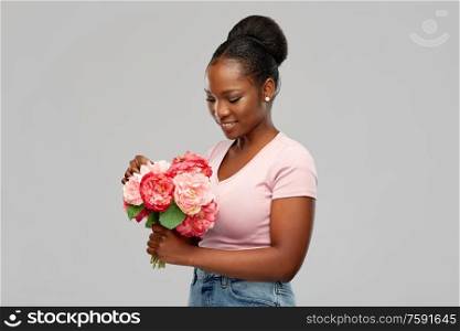 people and international women&rsquo;s day concept - happy african american young woman with bunch of peony flowers over grey background. happy african american woman with bunch of flowers
