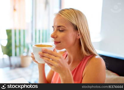 people and leisure concept - close up of happy woman drinking coffee at restaurant. close up of woman drinking coffee at restaurant