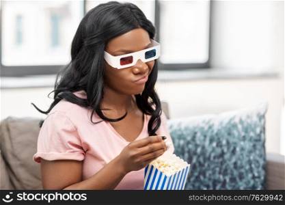 people and leisure concept - displeased african american young woman in 3d glasses watching tv and eating popcorn at home. bored african american woman watching tv at home